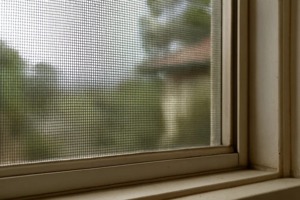 A fine metal mesh screen fixed over an openable window — bushfire screens and mesh, Adelaide Hills. Illustrative example.